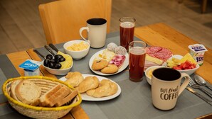 A breakfast table with various food items, including bread, pastries, and a coffee mug.