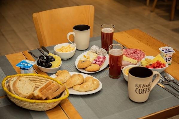 A breakfast table with various food items, including bread, pastries, and a coffee mug. - Hotel Inti Kuyen Plaza (Pucón)