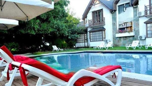 A swimming pool with lounge chairs and a covered area.