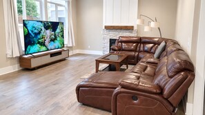 Una sala de estar con un sofá de cuero, una mesa de centro y un televisor de pantalla plana.