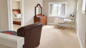 Quarto com cama, cômoda, escrivaninha e cadeira.