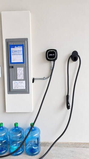 Dispensador de água fixado na parede, com painel de controle e mangueira conectada a garrafas de água.