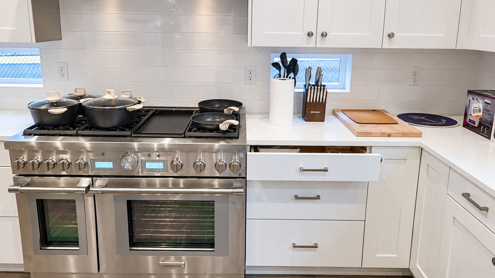 A modern kitchen with stainless steel appliances, white cabinetry, and a window with a view.