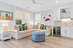 A living room with a sectional sofa, ottoman, and a wall mural.
