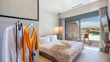 Ein Hotelzimmer mit einem großen Bett, einem Schreibtisch, einem Fernseher und Blick auf einen Pool und die Landschaft.