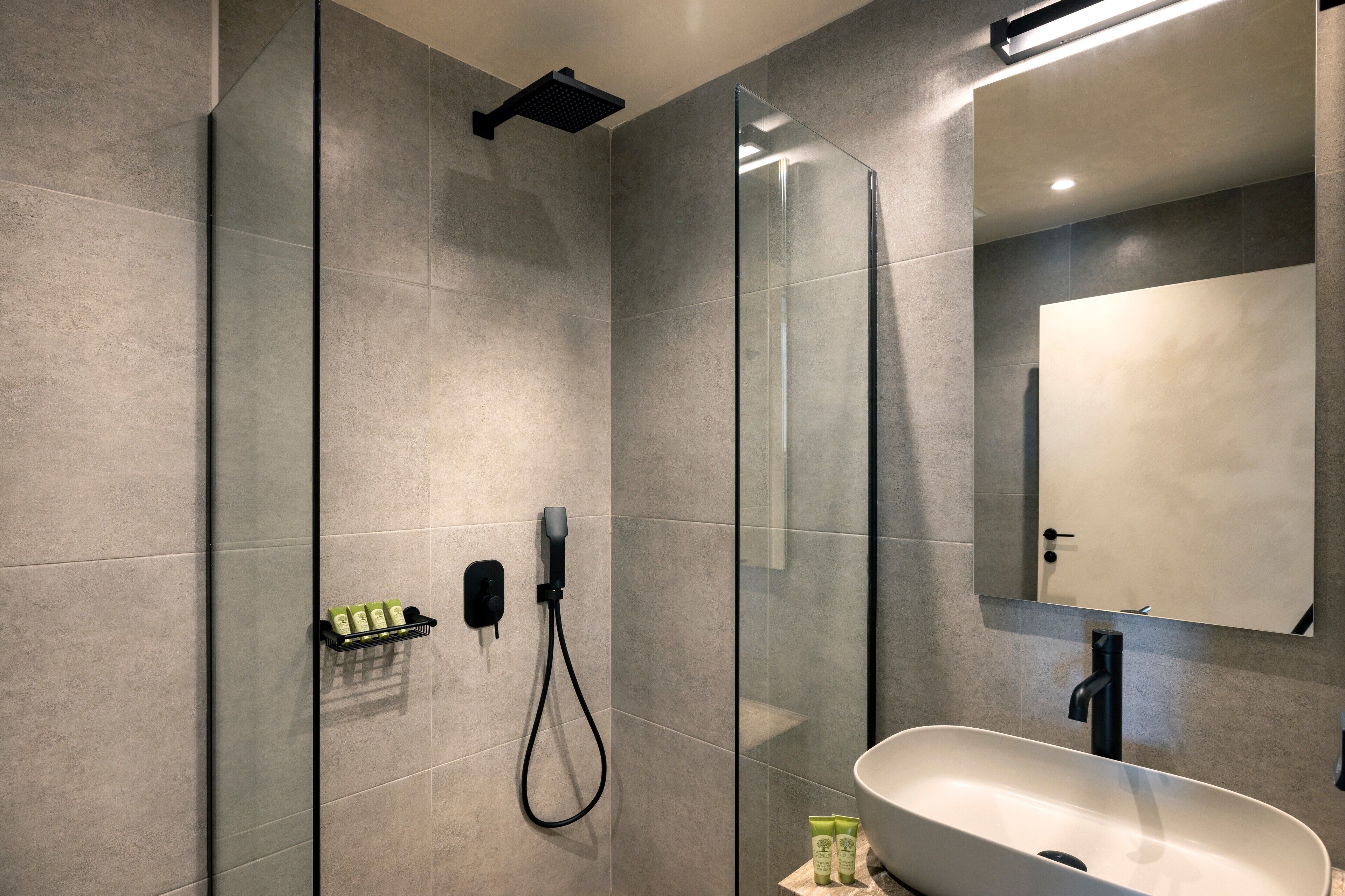 Un bany modern amb un espai de banyera de vidre, un mirall gran i un lavabo independent.