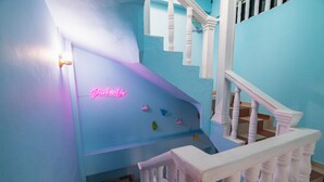 A staircase with a blue wall and a neon sign reading "Dawkins." - San Felicin Hostel (Cartagena)