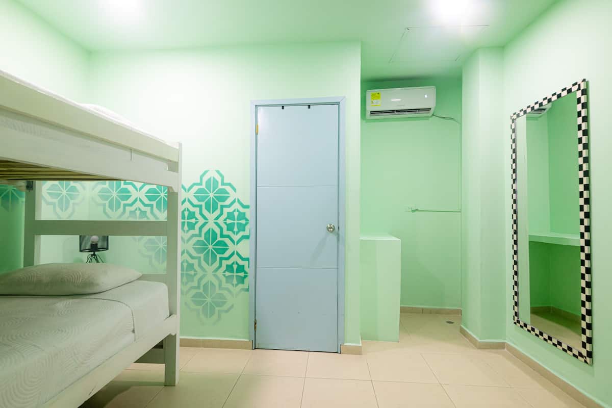 A room with a bunk bed, a door, an air conditioning unit, and patterned walls.