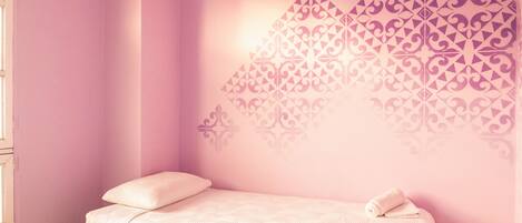 A bedroom with a bed, a window, and a wall with a decorative pattern.
