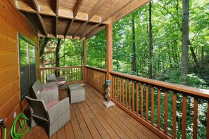 Eine Holzterrasse mit Korbmöbeln und Blick auf einen Wald.