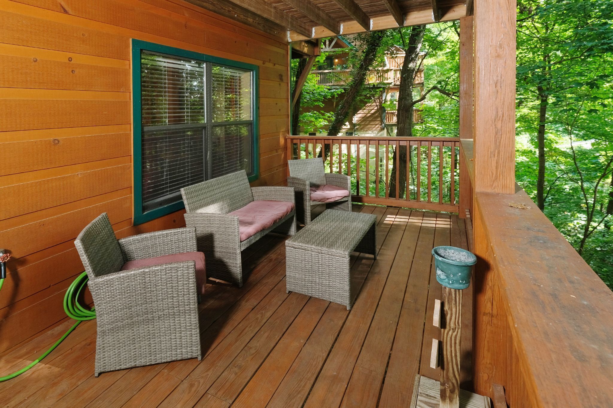 A wooden deck with wicker furniture and a view of a forest.