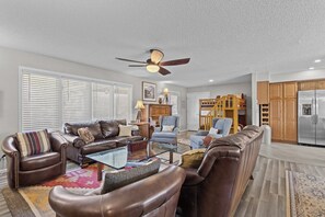 A living room with a brown leather sofa, a glass coffee table, and a ceiling fan. - Lazy Days M-01A - Three Bedroom House, Sleeps 10 (Osage Beach)