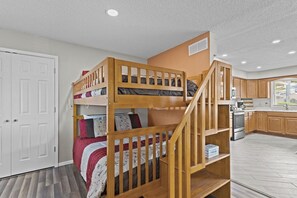 A bunk bed with a wooden staircase, a kitchen area with wooden cabinets, and a white door. - Lazy Days M-01A - Three Bedroom House, Sleeps 10 (Osage Beach)