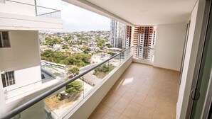 Un balcone con vista sulla città, pavimento piastrellato e ringhiera in vetro.