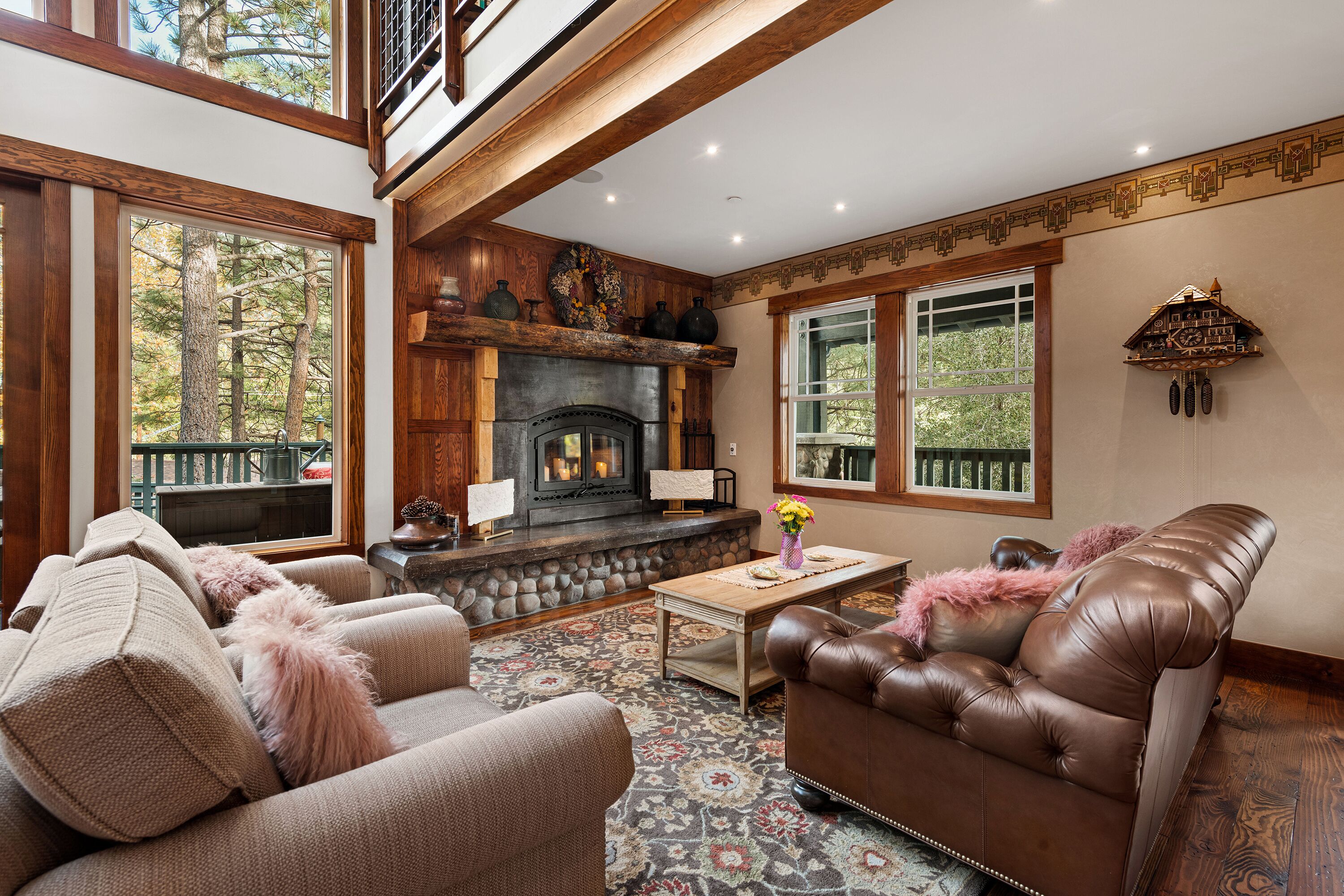A cozy living room with a fireplace, leather sofa, and a patterned rug.