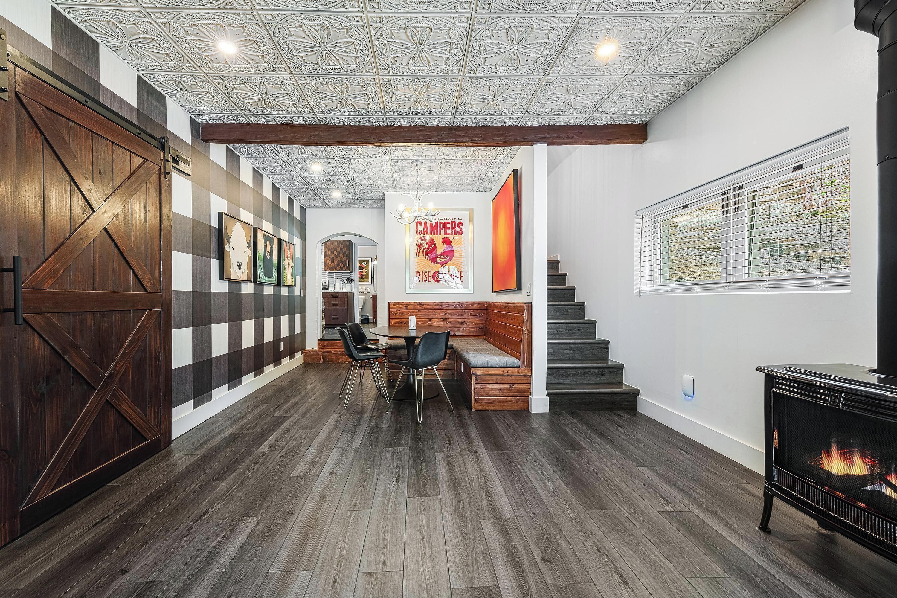 A spacious living area with a wooden floor, a fireplace, and a staircase leading to another level.