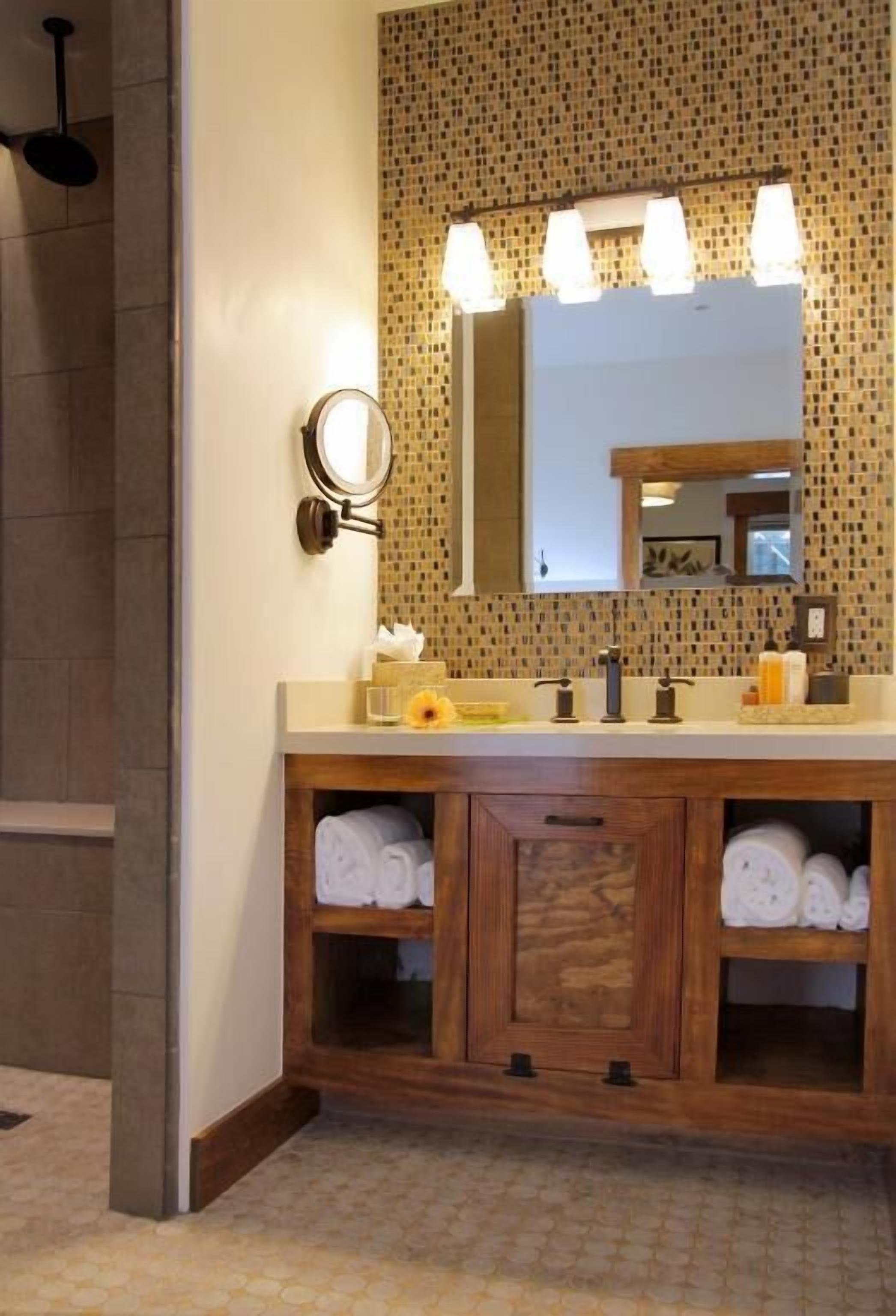 Un baño con tocador de madera, un espejo y salpicadero de azulejos.