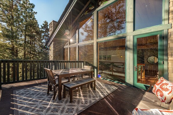 A patio with a wooden table and chairs, a bench, and a patterned rug. - The Grand Idyllwild Lodge (Idyllwild)