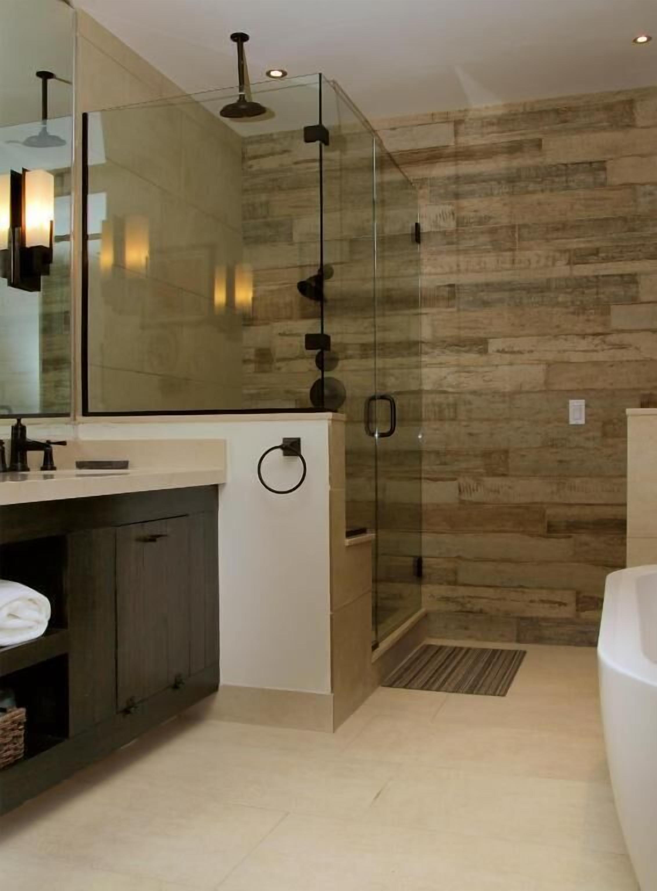 Un baño moderno con cabina de ducha de vidrio, un espejo grande y una pared de madera.