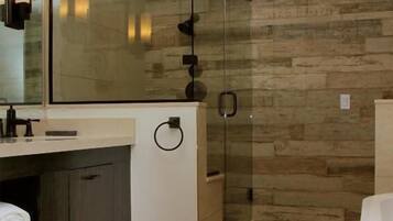Un baño moderno con cabina de ducha de vidrio, un espejo grande y una pared de madera.
