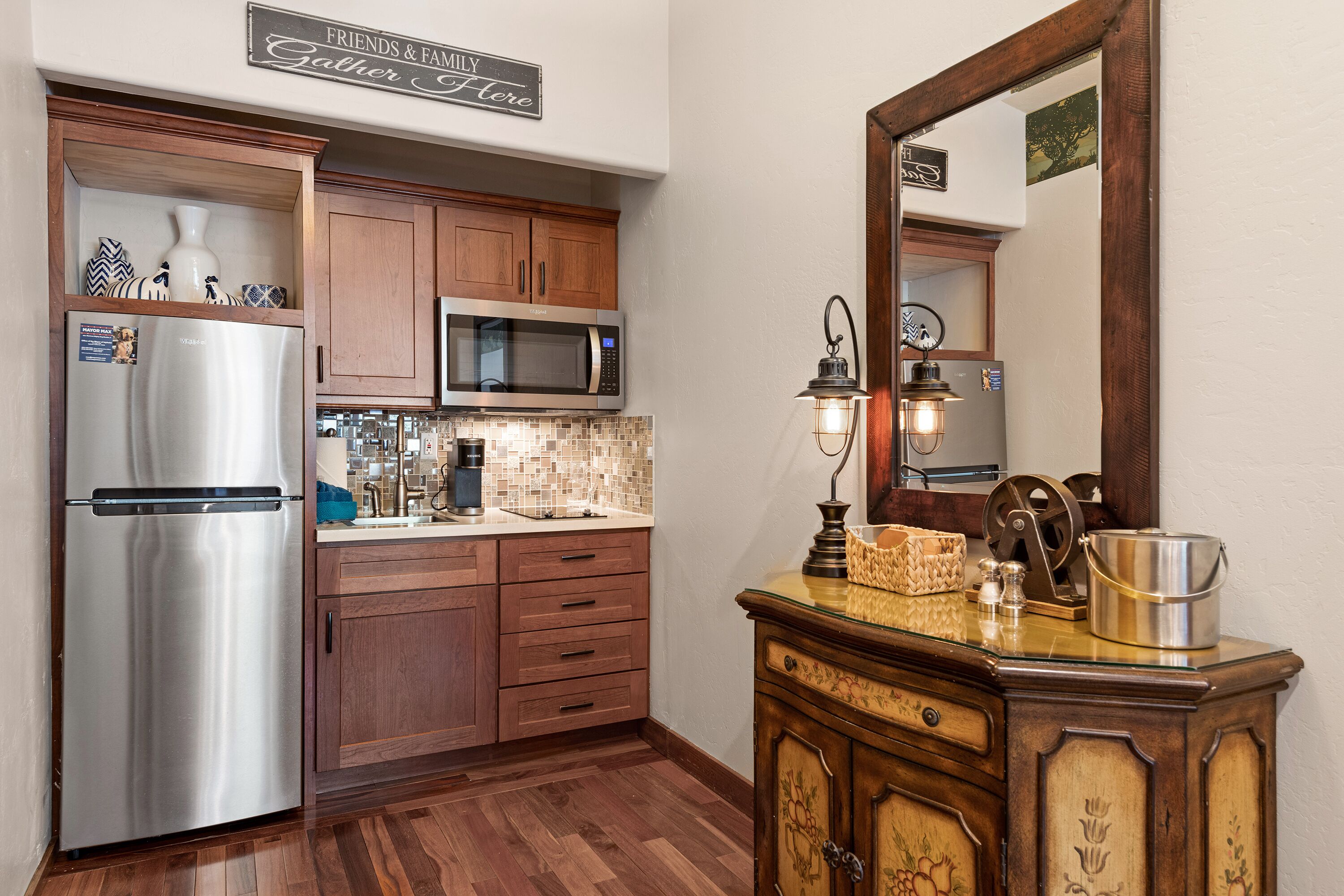 Una cocina con armarios de madera, electrodomésticos de acero inoxidable, salpicadero de azulejos y un espejo sobre la encimera.
