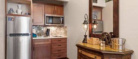 Una cocina con armarios de madera, electrodomésticos de acero inoxidable, salpicadero de azulejos y un espejo sobre la encimera.