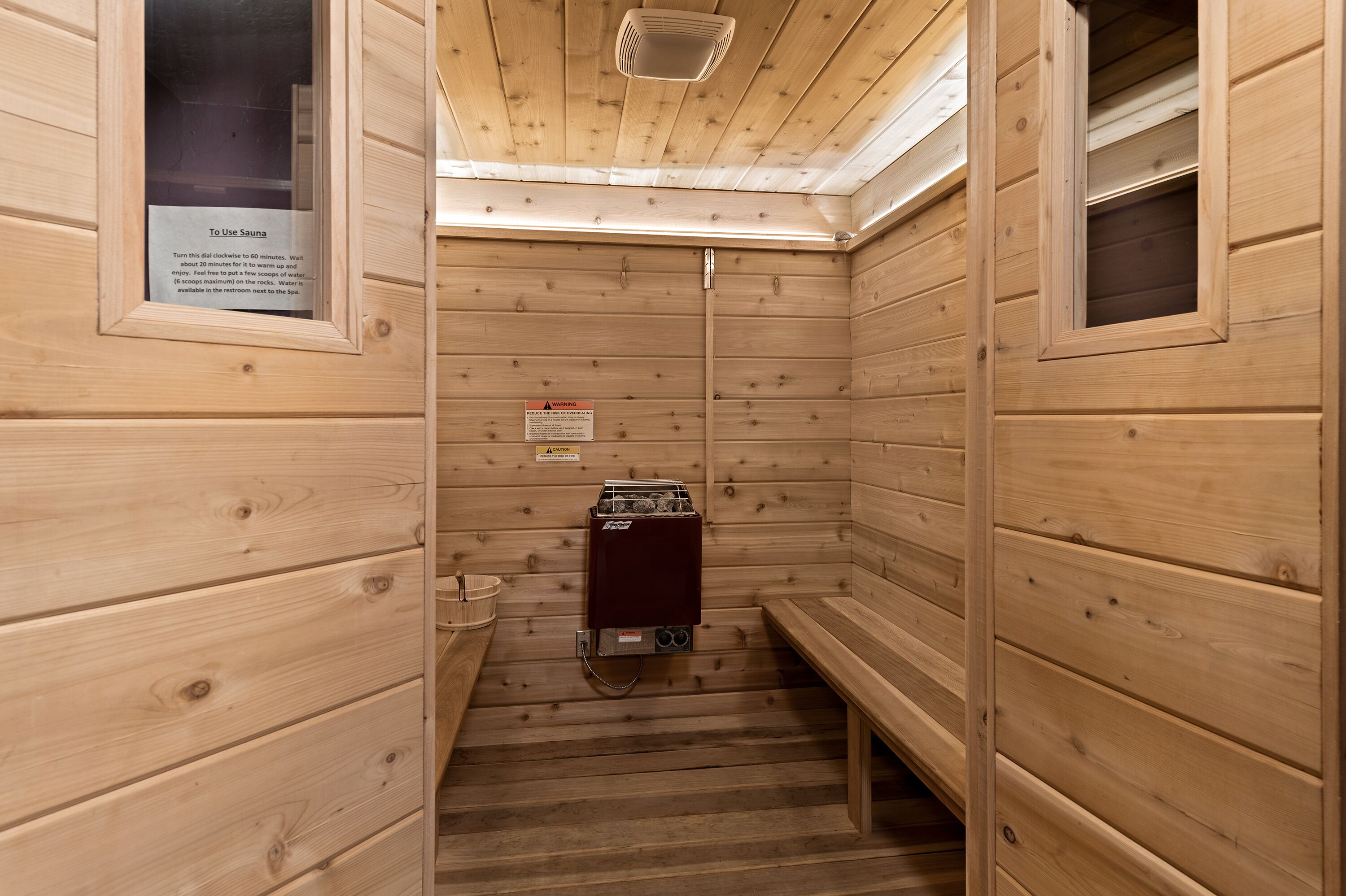 Une salle de sauna avec des murs en bois, un banc, un appareil de chauffage et un panneau indiquant la manière d’utiliser le sauna.