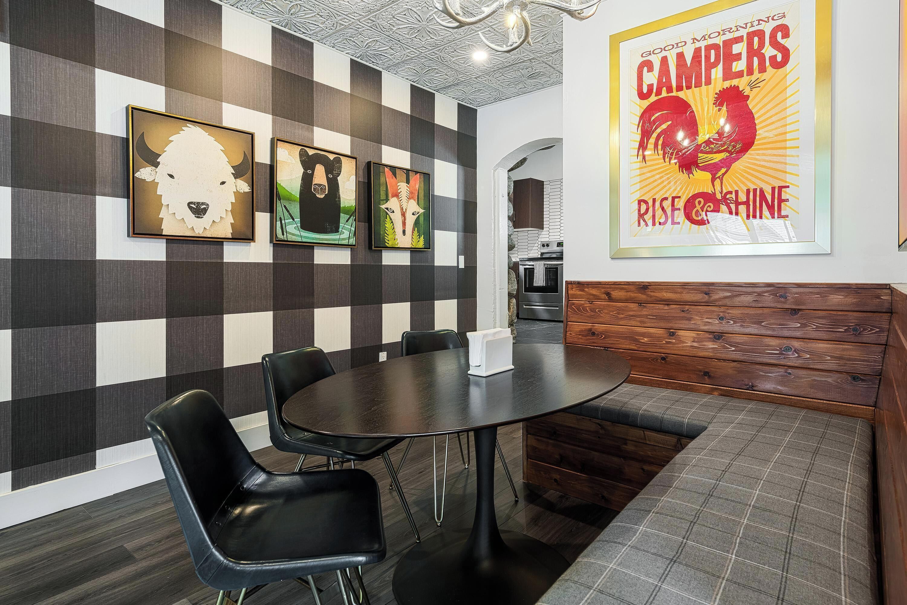Una cocina moderna con una pared a cuadros, una zona de comedor con una mesa redonda y sillas, y un banco.