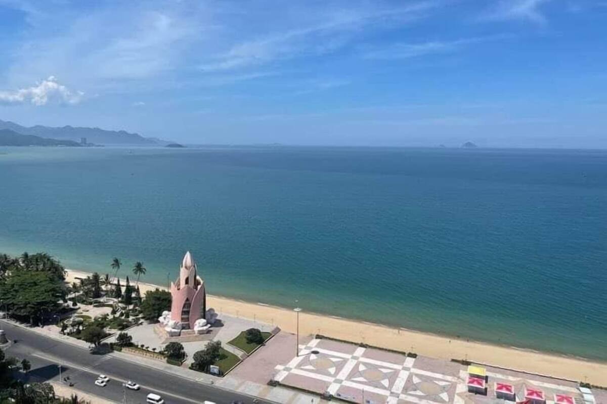 Vista costera con una torre rosa destacada, una playa y cielo despejado.
