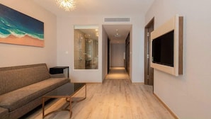 A modern living room with a sofa, coffee table, and a TV mounted on the wall.