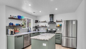 A modern kitchen with a central island, built-in appliances, and a window providing natural light. - Zion Luxe Family Escape: HotTub, Games, Sleeps 14 (Glendale)