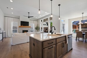 Une cuisine spacieuse dotée d’un grand îlot central, de meubles en bois et de luminaires suspendus.
