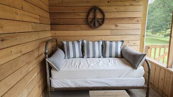Una cabaña de madera con una cama, almohadas y una pequeña mesa.
