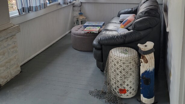 A cozy living room with a black leather sofa, a small ottoman, and a window with striped curtains. - Central to Everything ...Cedar Point, Downtown and Sports Park.   (Sandusky)