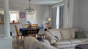 A living room with a beige sofa, a dining table with chairs, and a kitchen area in the background. - Central to Everything ...Cedar Point, Downtown and Sports Park.   (Sandusky)