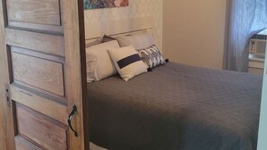 A bedroom with a bed, a wooden door, a wall-mounted artwork, and a ceiling light fixture. - Central to Everything ...Cedar Point, Downtown and Sports Park.   (Sandusky)