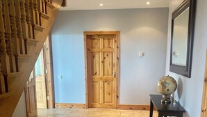 A hallway with a wooden staircase, a wooden door, and a small table with a globe. - (Family and pet friendly), Inishmore, Aran Islands, Large spacious property! (Creig a'Chéirin)