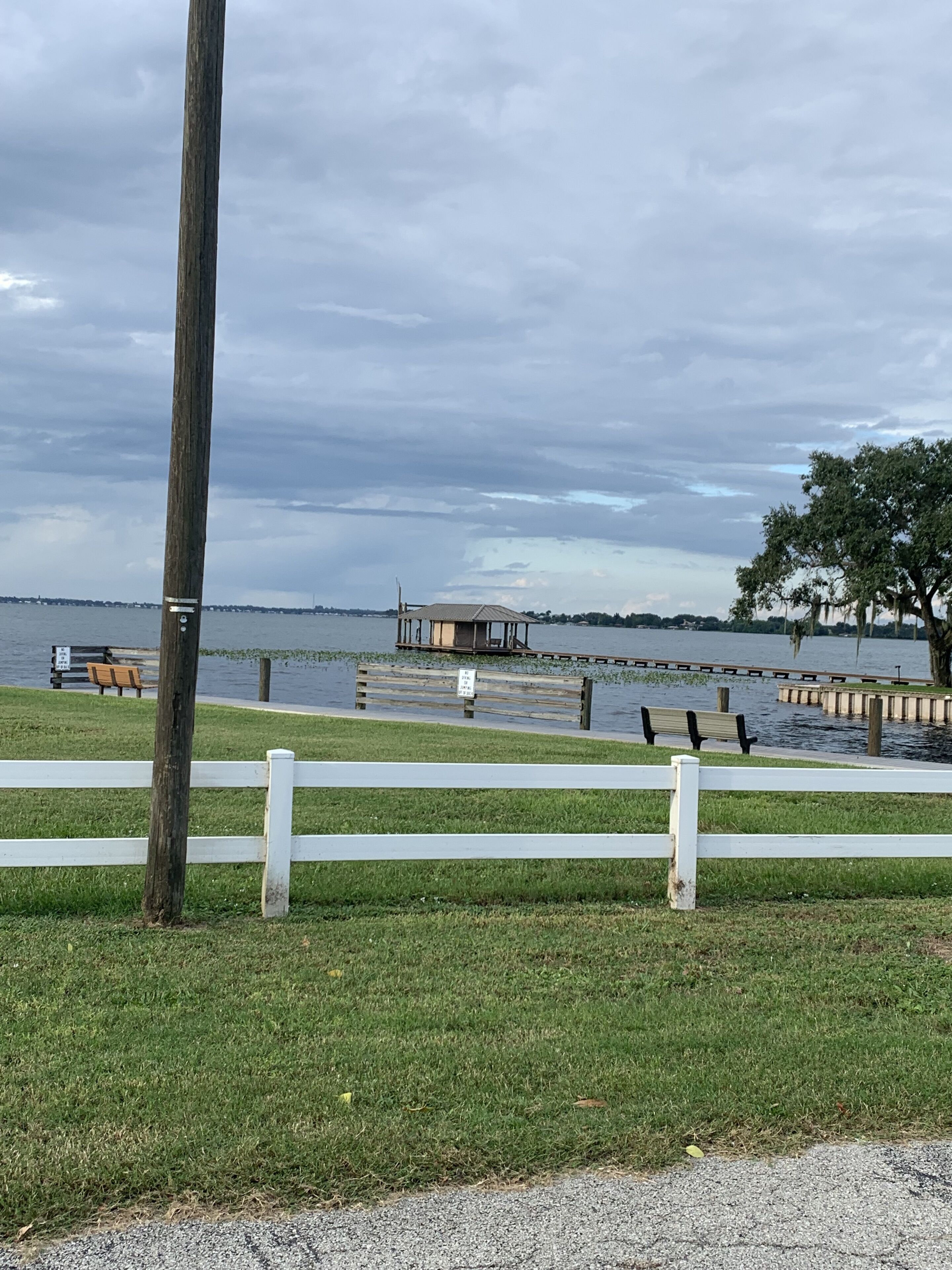 Un parc au bord de l’eau, doté d’une jetée en bois, de bancs et d’une pelouse.