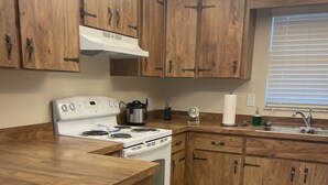 A kitchen with wooden cabinets, a white stove, and a stainless steel sink. - El Palacio de la Pesca (Lake Placid)