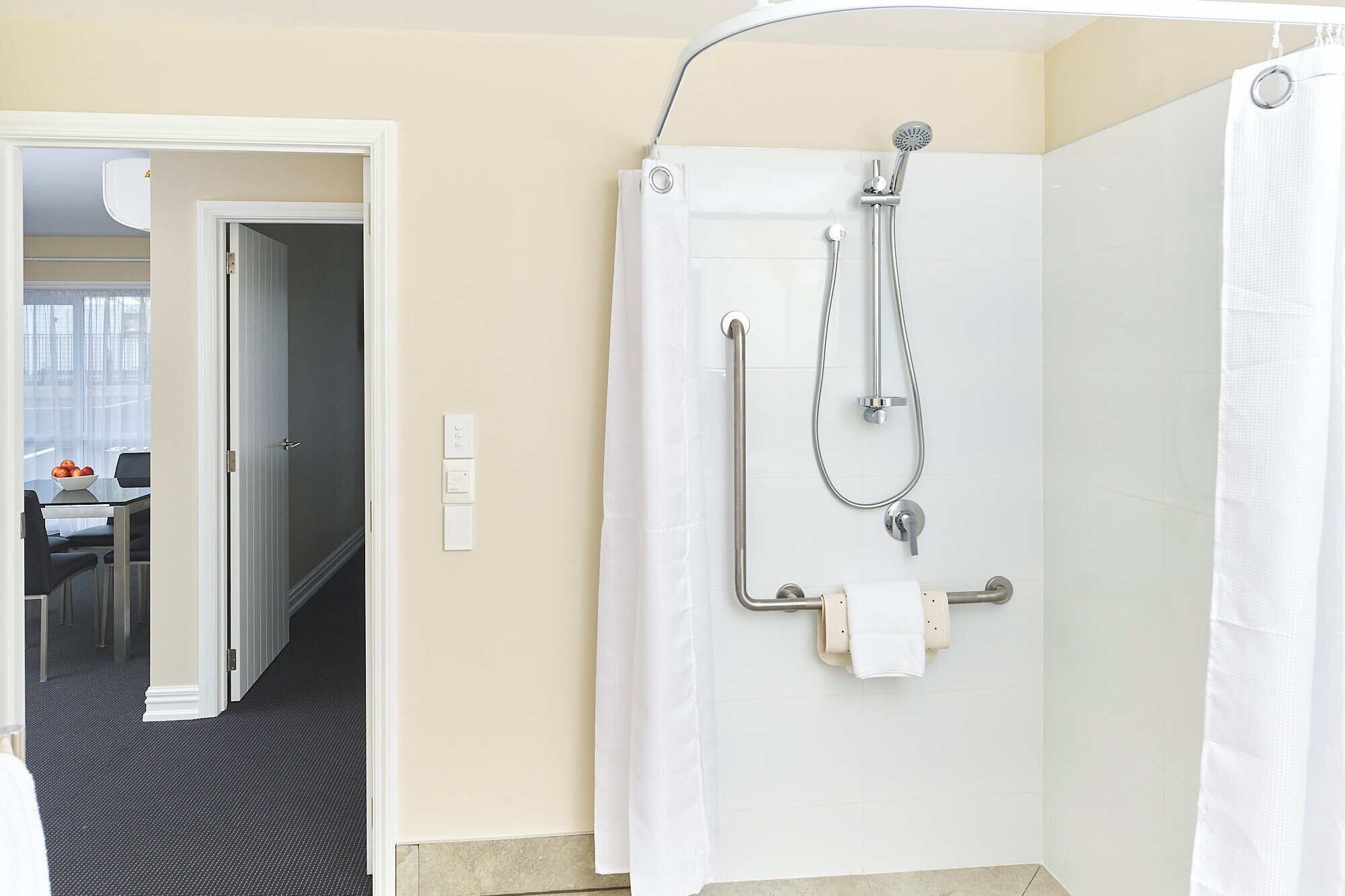Un baño con ducha, inodoro y un perchero para toallas.