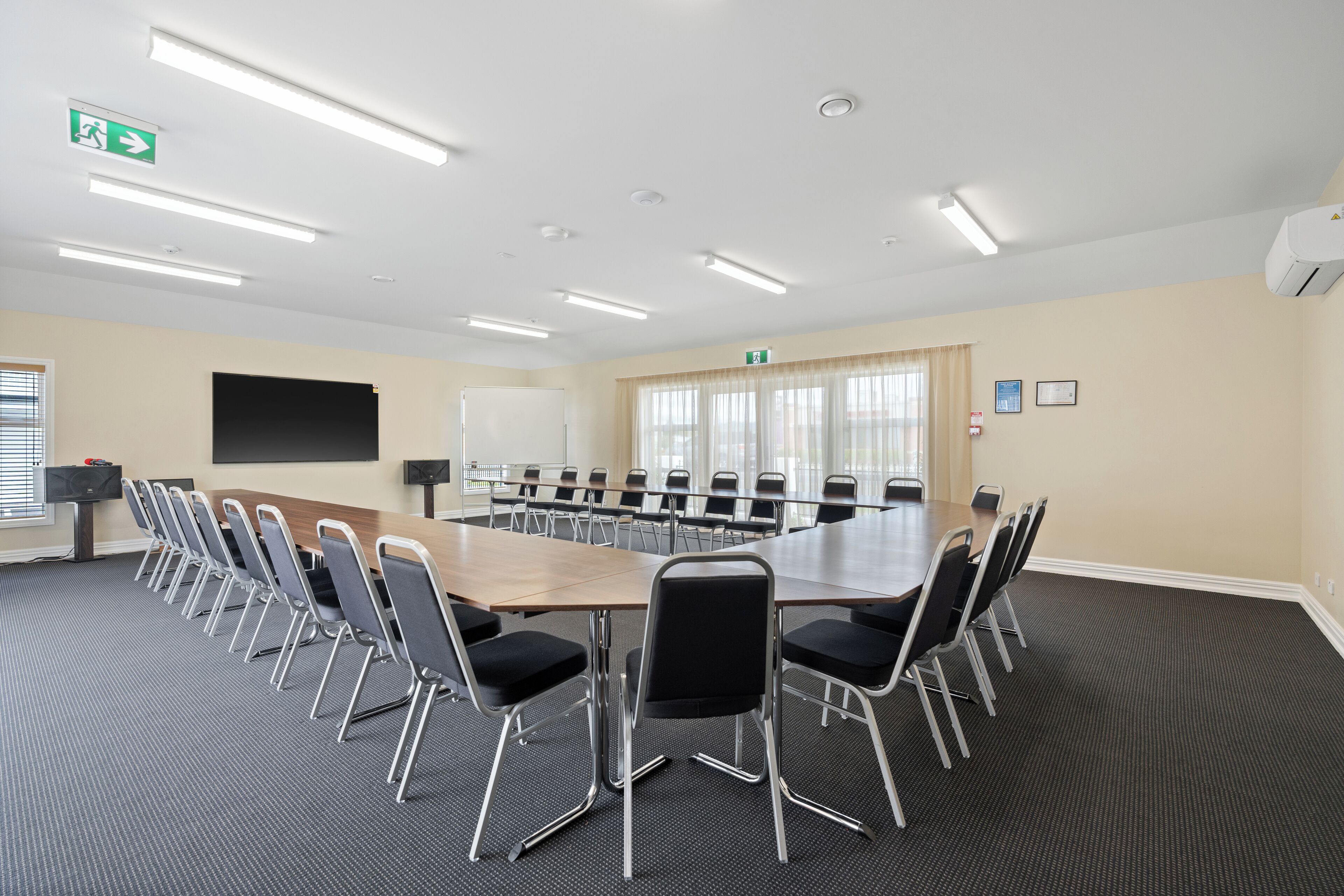 A conference room with a large table, chairs, a projector screen, and a whiteboard.