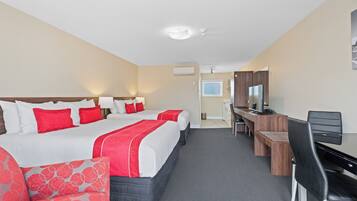 A hotel room with two beds, a desk, a chair, a TV, and a window.