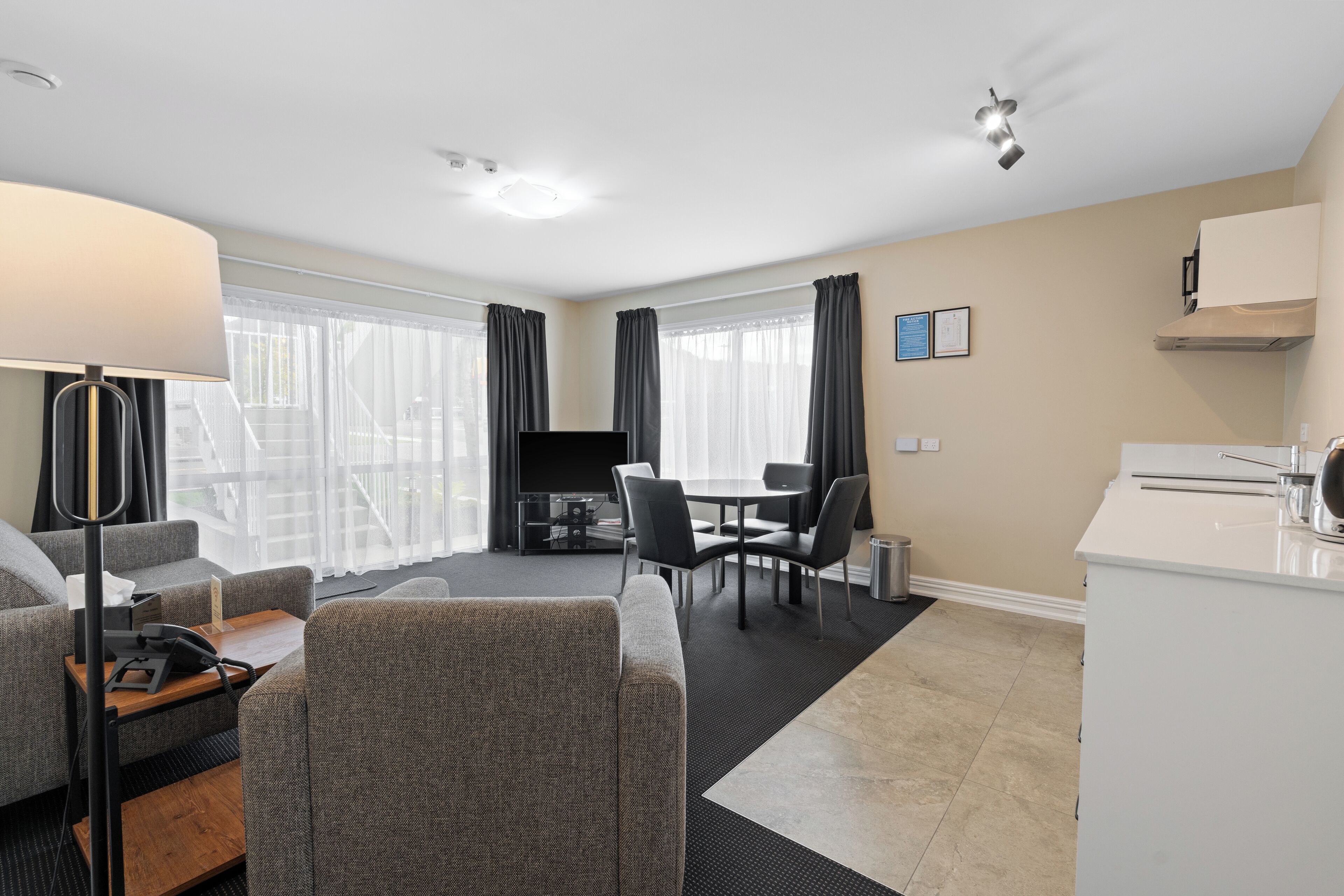 A modern hotel room with a living area, dining space, and kitchenette.