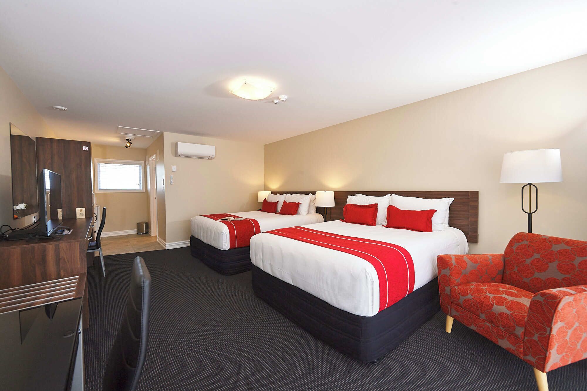 Een hotelkamer met twee bedden, een bureau, een stoel en een lamp.