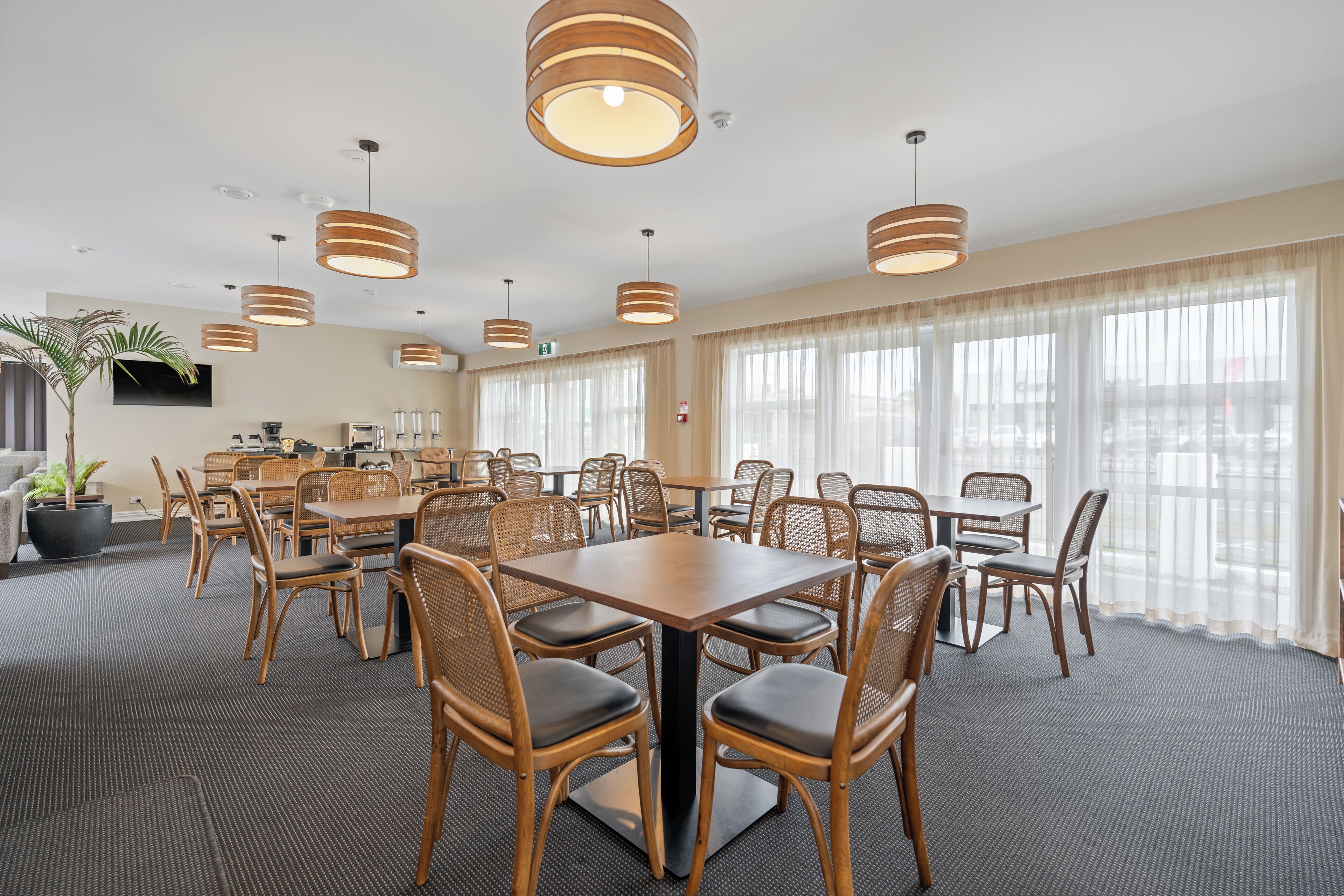 A conference room with round tables, wooden chairs, and pendant lighting.