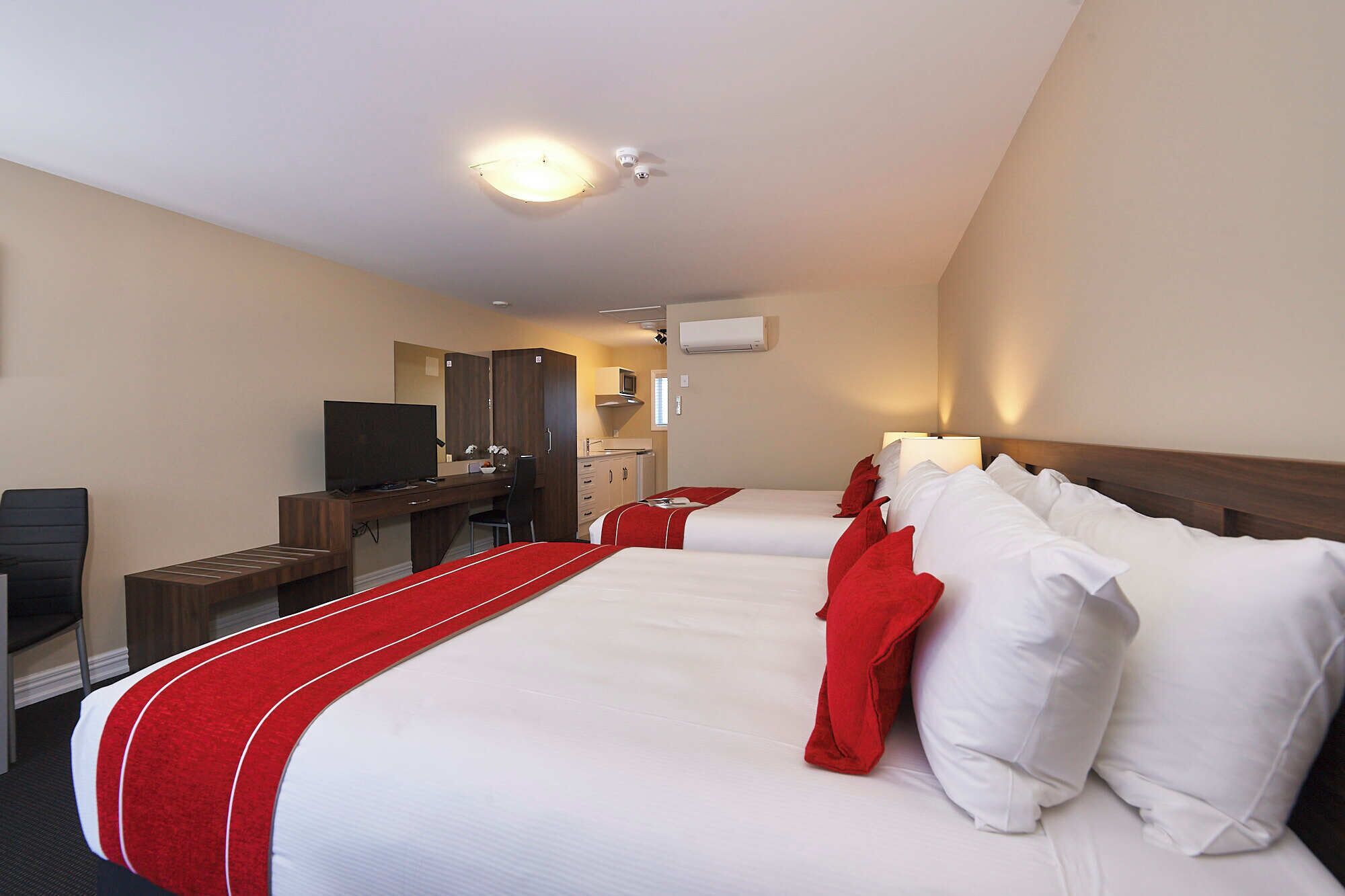 Habitación de hotel con una cama grande, un escritorio con ordenador, un televisor y un armario.