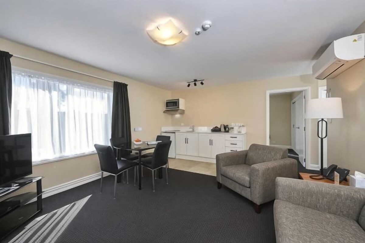 Une chambre d’hôtel comprenant un coin repas, une kitchenette et un espace de vie avec un canapé et une télévision.