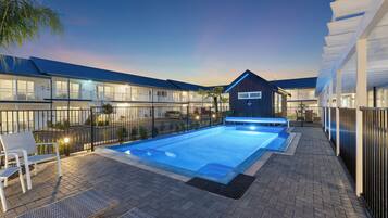 Una piscina al aire libre, sombrillas, sillones reclinables de piscina