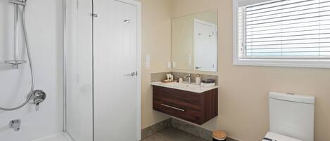Une salle de bain équipée d’une douche, de toilettes, d’un lavabo et d’une fenêtre avec des stores.