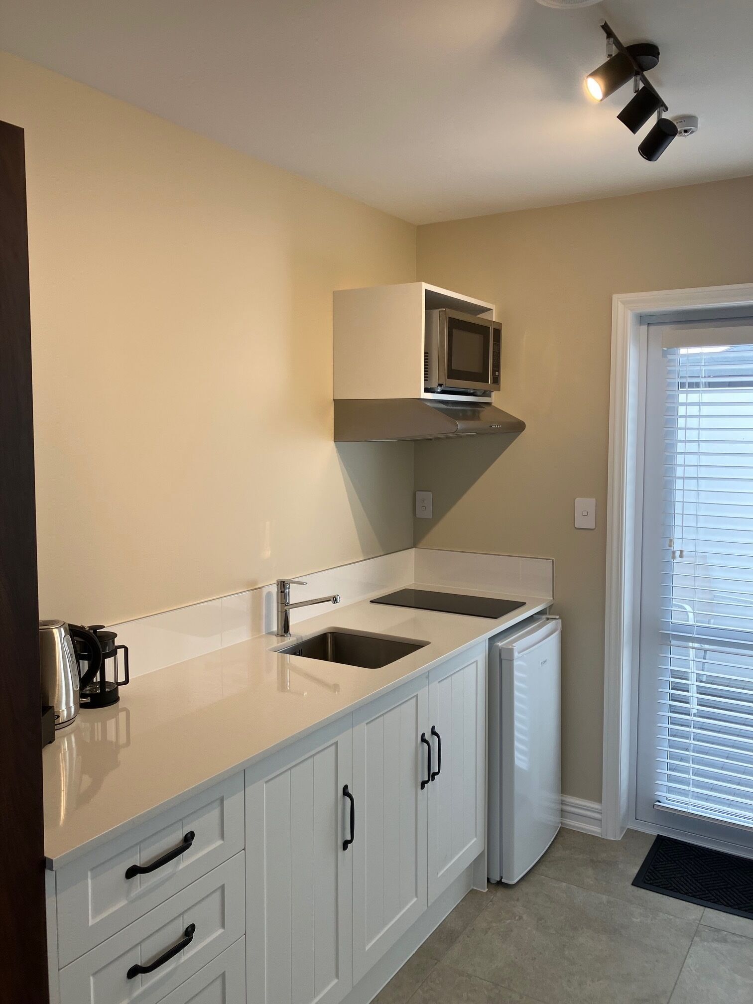 A modern kitchen with white cabinets, a built-in microwave, and a coffee maker.